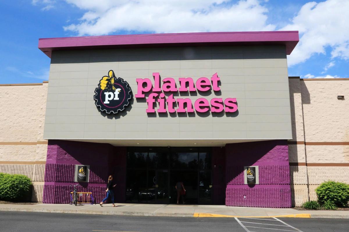 Brightly lit Planet Fitness gym exterior with pink and purple branding, showcasing a modern fitness center promoting health, wellness, and physical activity for all fitness levels.