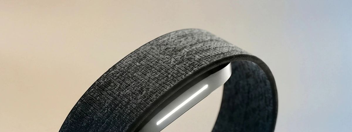 Close-up of a black fabric Hume Band with a white indicator light against a pale background.