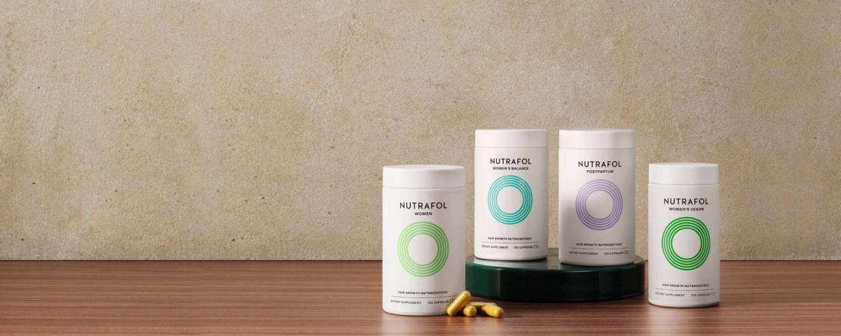 Nutrafol hair growth supplement bottles on a wood table