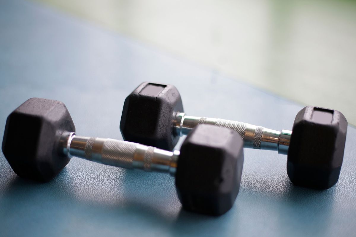 Two black hex dumbbells with silver handles on a blue exercise mat.