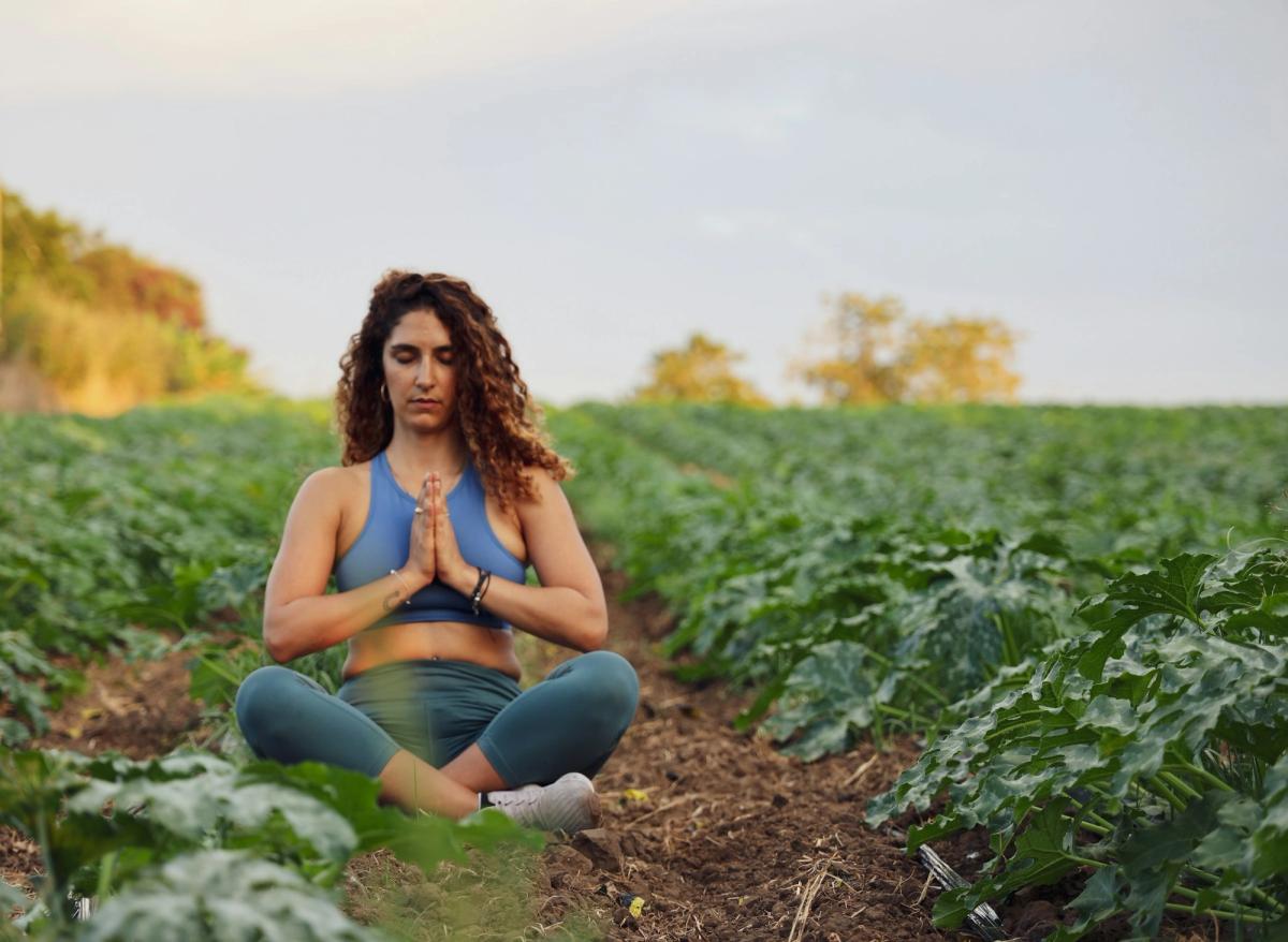 Woman meditating cross-legged outdoors at sunset