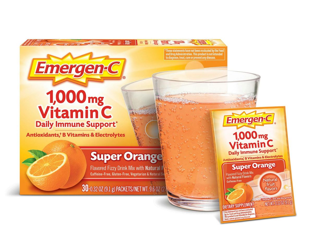Emergen-C Super Orange box and packet beside a glass of orange drink on a white background.