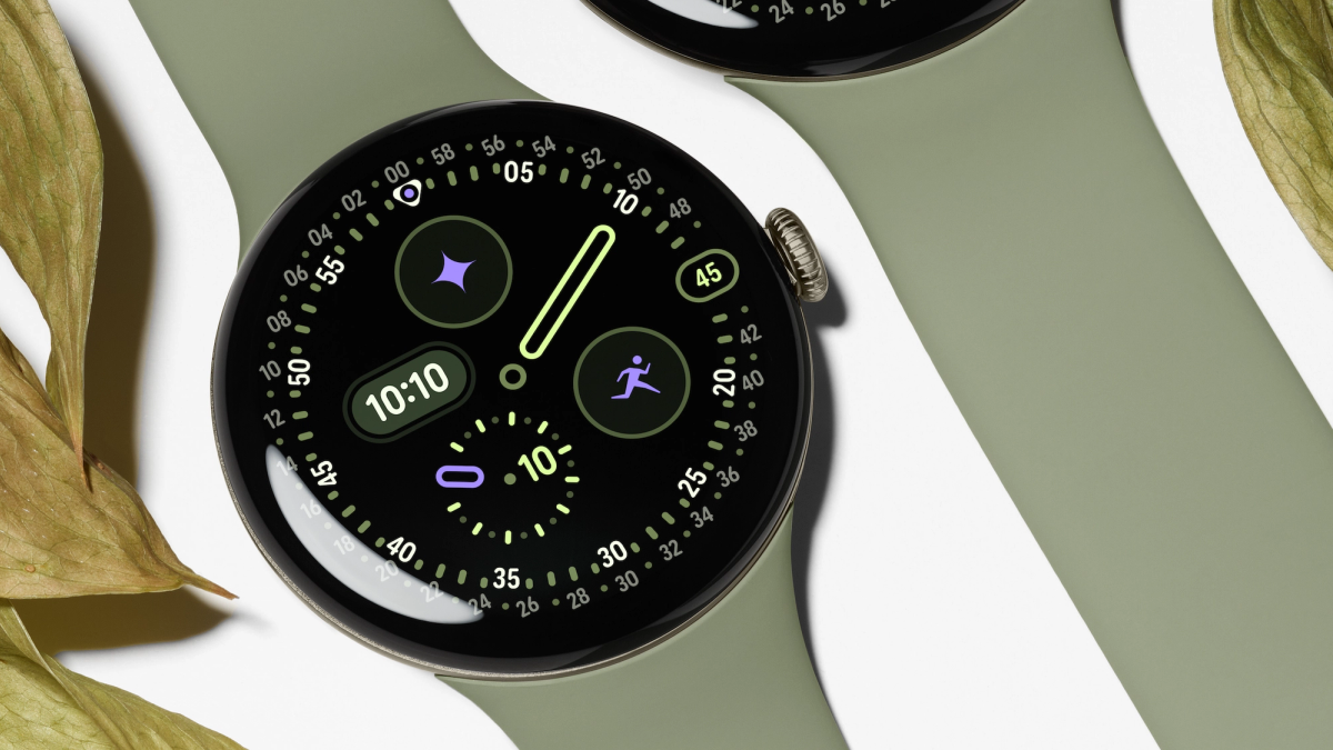 Google Pixel Watch 5 with an olive green band and a round black watch face beside leaves