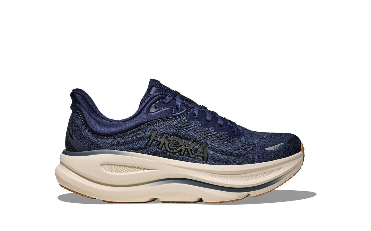 A navy HOKA running shoe with a thick cushioned cream midsole shown in profile