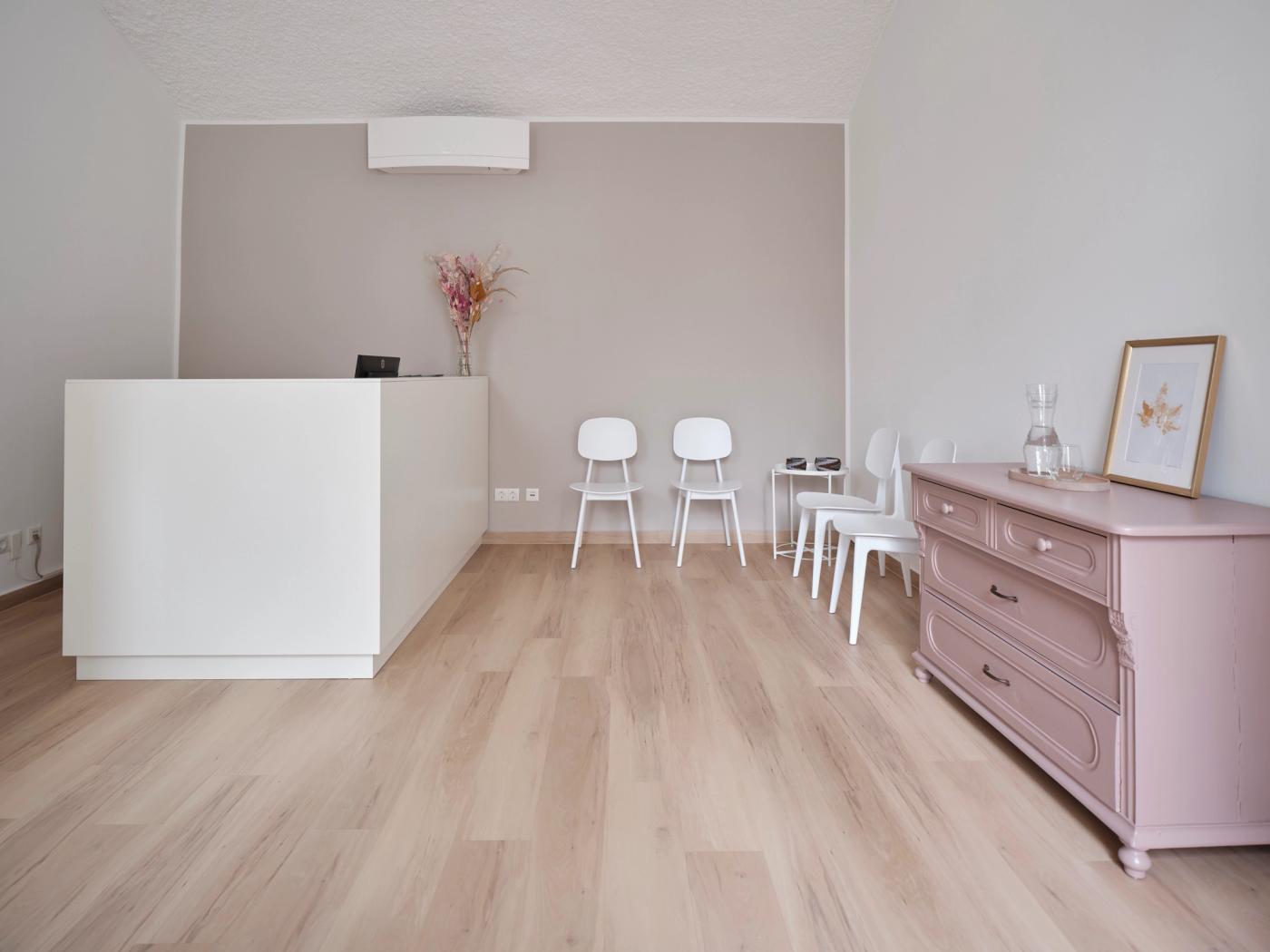 Der Warteraum unter der weißen Gewölbedecke, mit dem weißen Empfangspult links und der mauve gestrichenen Vintagekommode rechts an der Wand.
