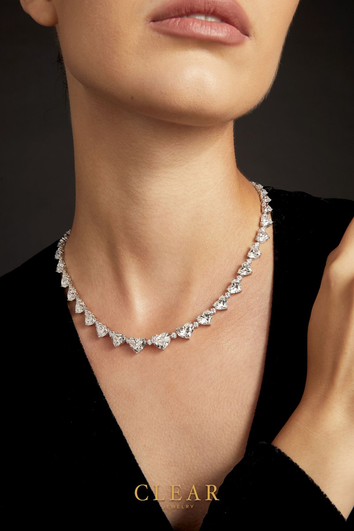 Heart-shape diamond rivière necklace worn against black velvet.