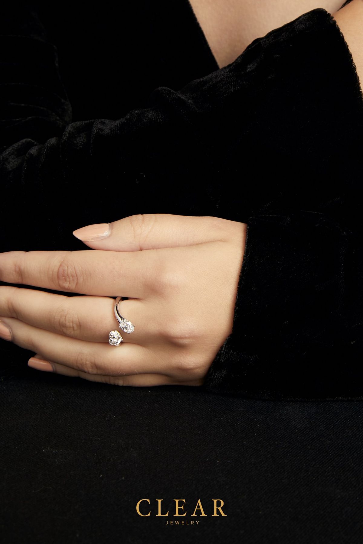 Two-stone diamond toi-et-moi ring on a hand resting against black velvet.