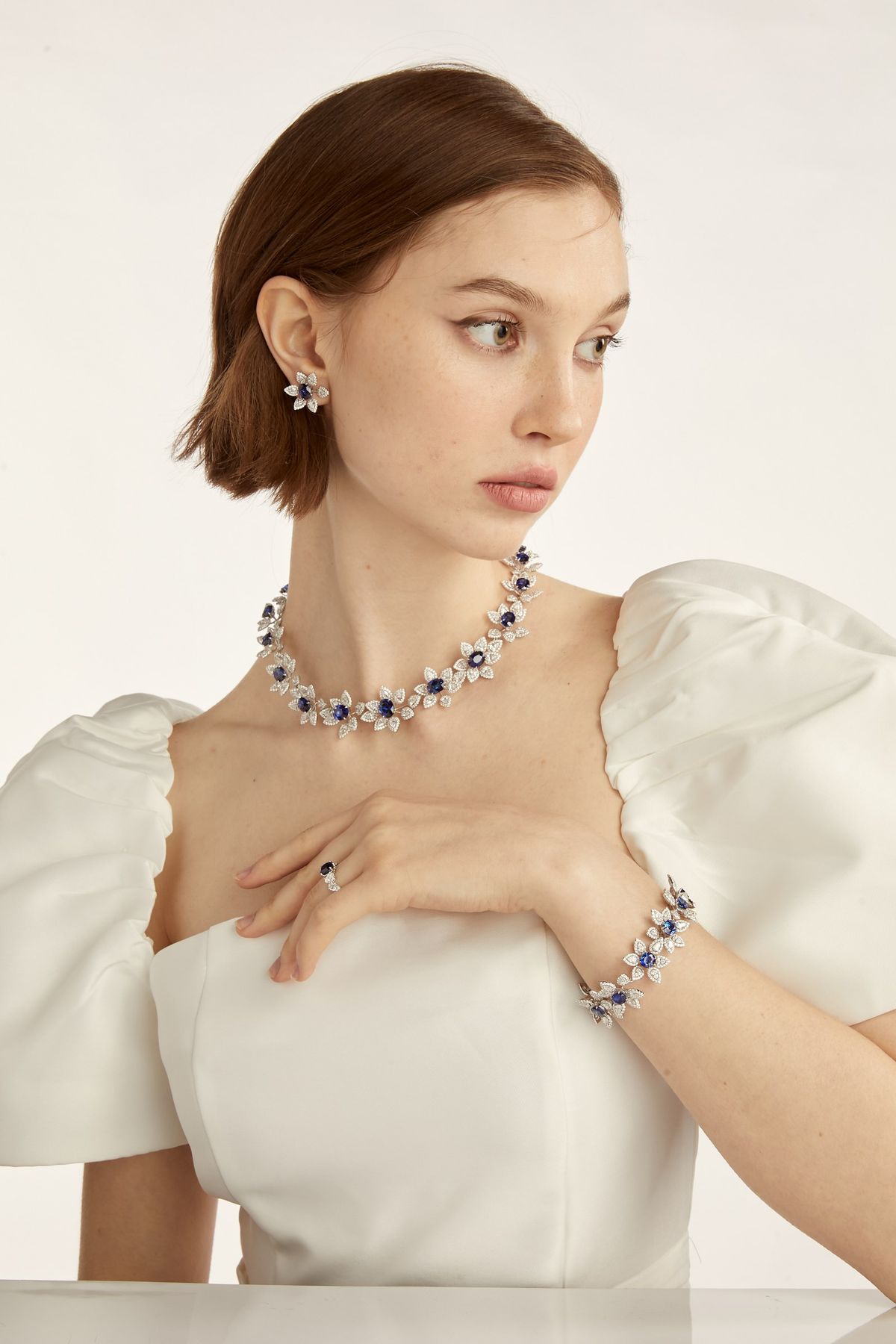 Model in ivory bridal silhouette wearing the sapphire floral suite.