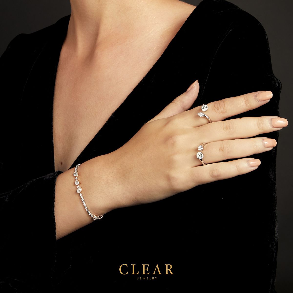 A slender tennis bracelet worn with two open diamond rings.