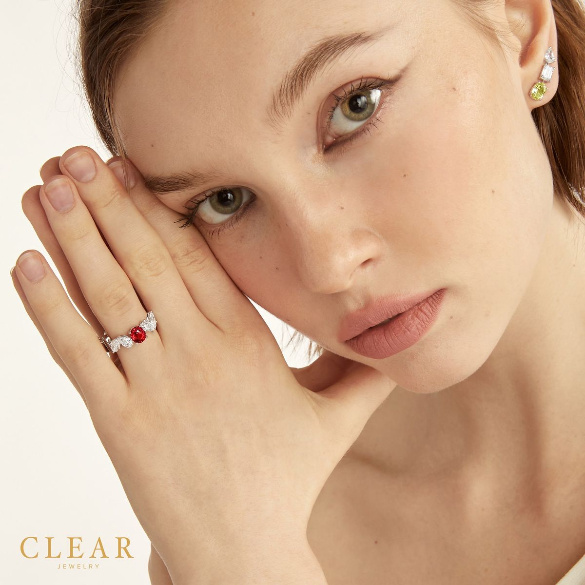Model with hand at temple wearing a Burmese ruby bypass ring and a fancy yellow diamond earring.