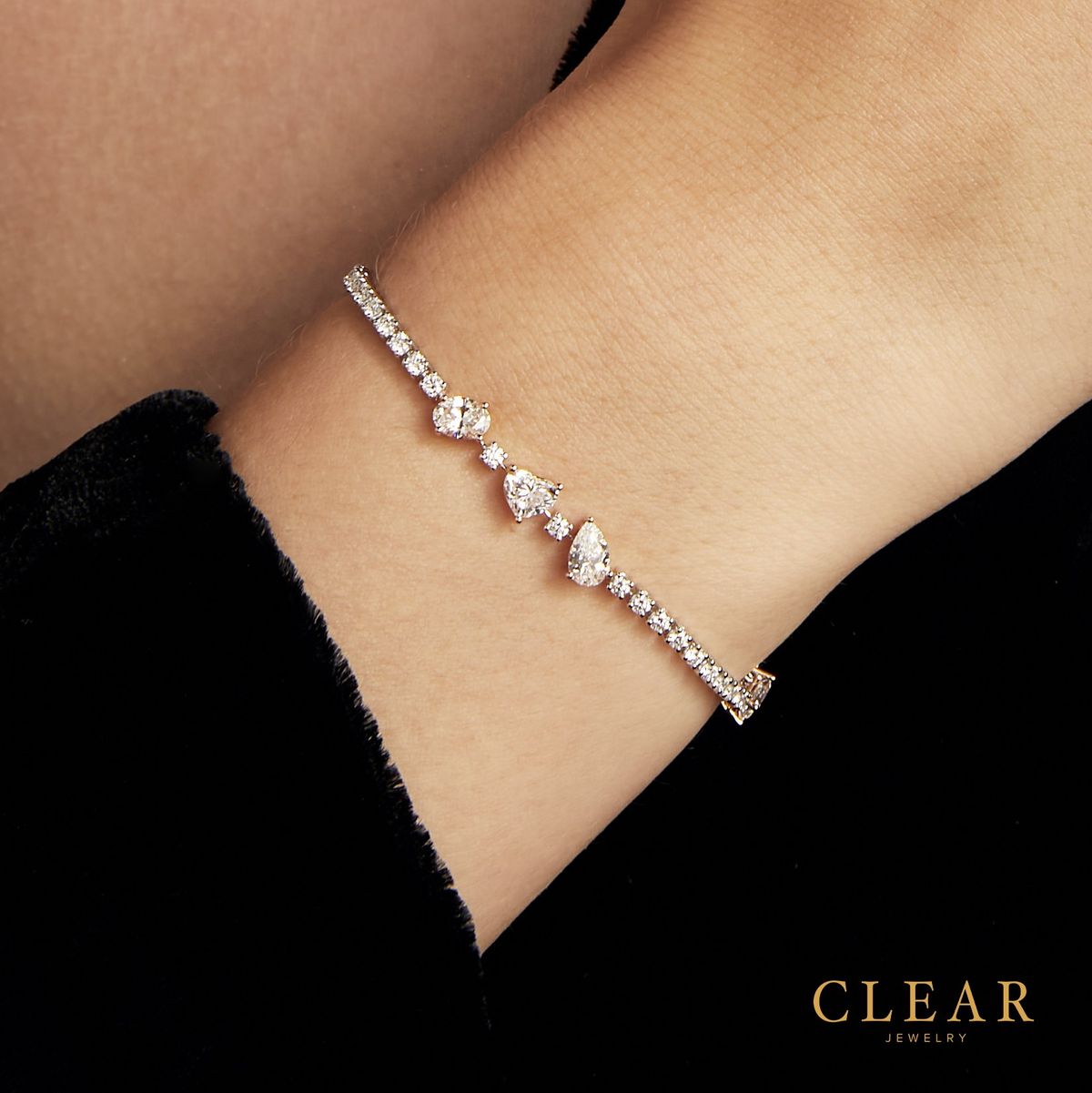 Diamond tennis bracelet with graduated pear diamonds, worn on the wrist.