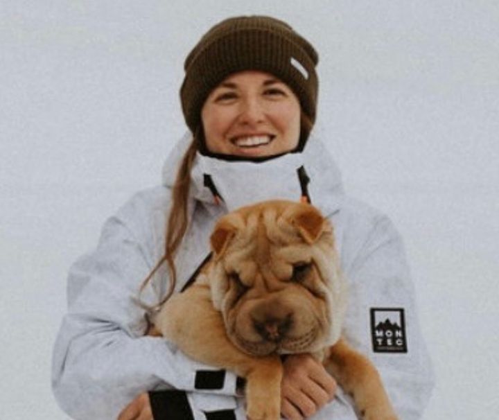 Anne Rarick smiling in the snow holding her dog Wrinkles