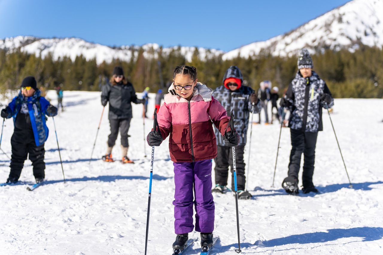 Washoe Tribe kids on cross-country skis on a sunny snowy meadow