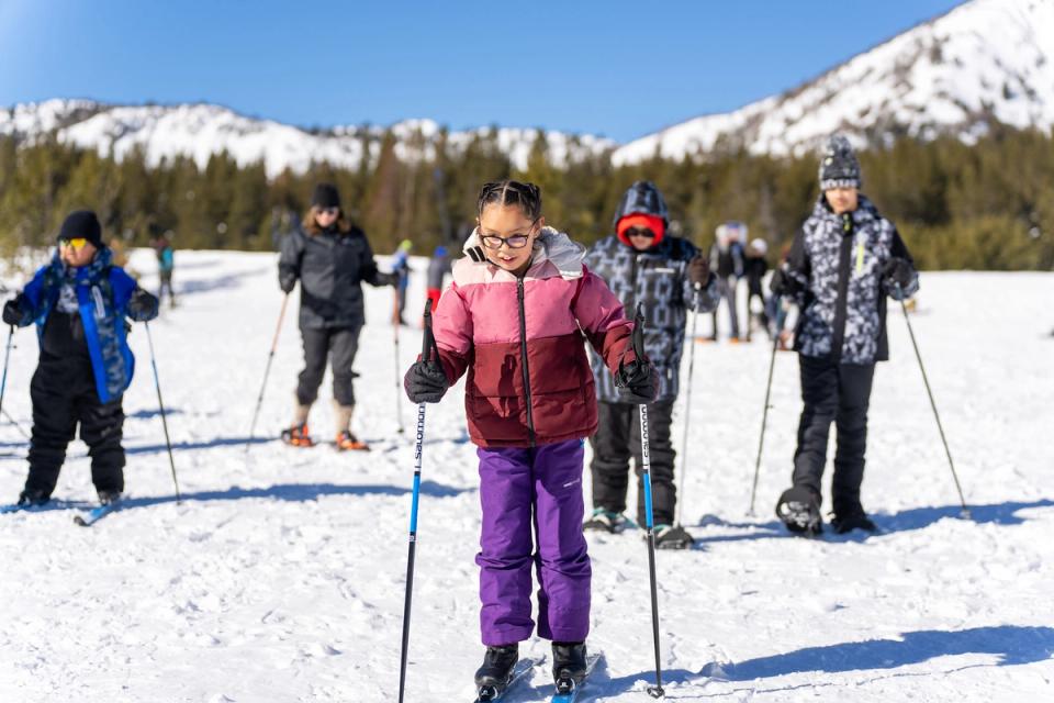 Washoe Tribe kids on cross-country skis on a sunny snowy meadow