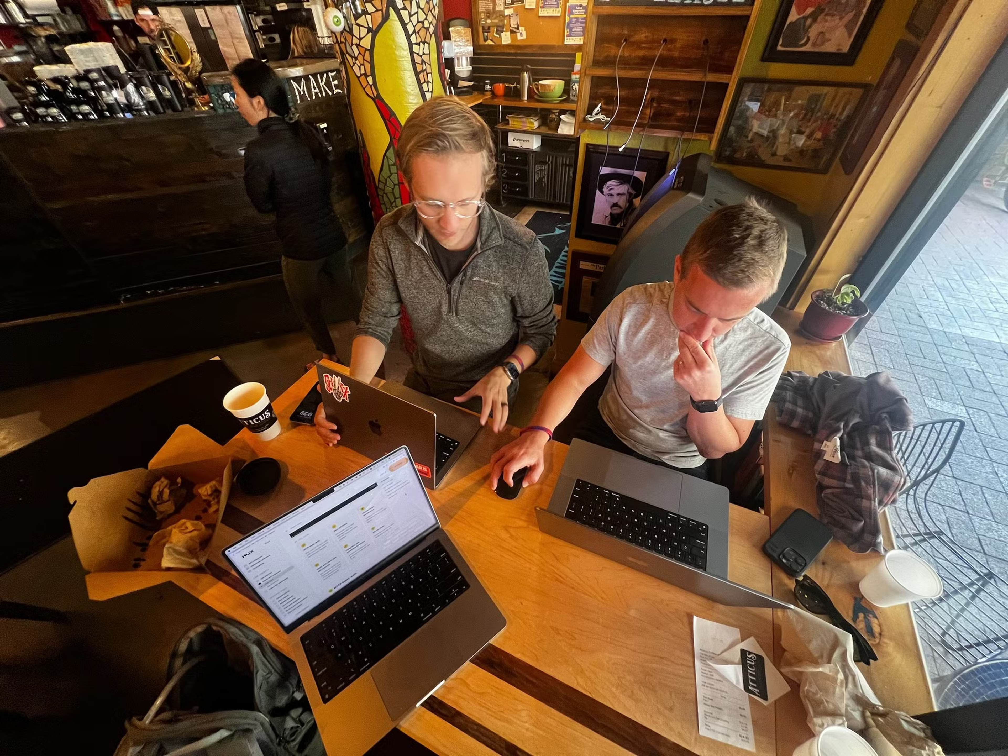 Dar and Rob working with intense focus at a coffee shop table.