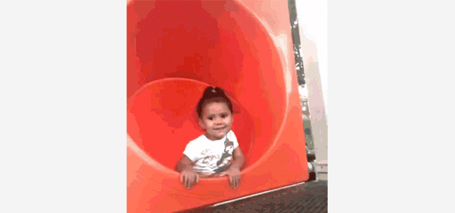 GIF of child waving and then sliding backwards down a slide. 