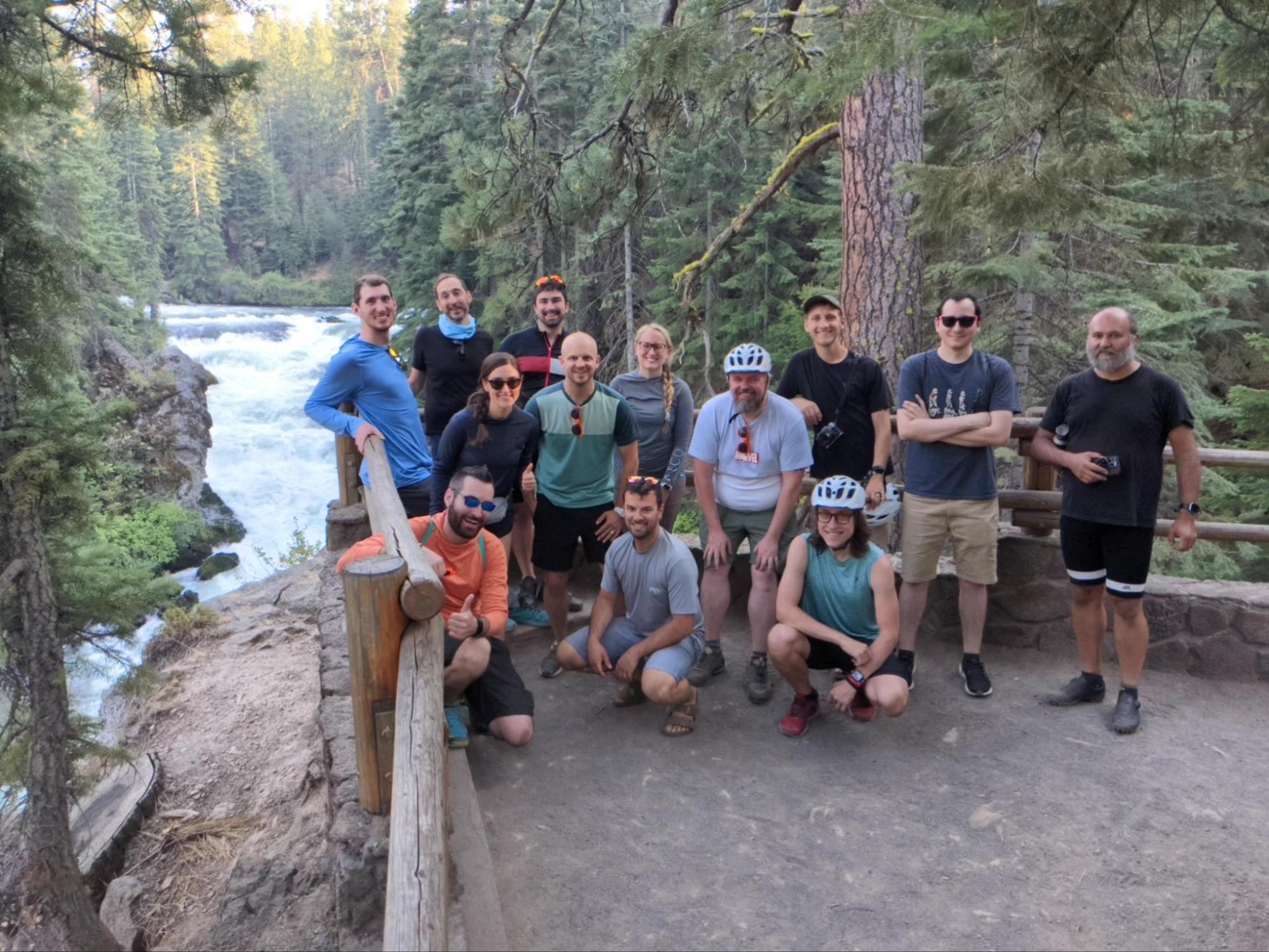 A group of cyclists posing in front of a waterfall in Central oregon