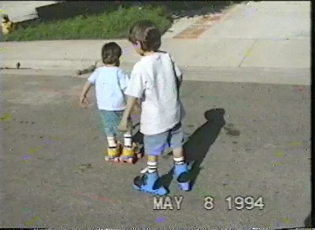 two young kids rollerblading on a suburban culdesac