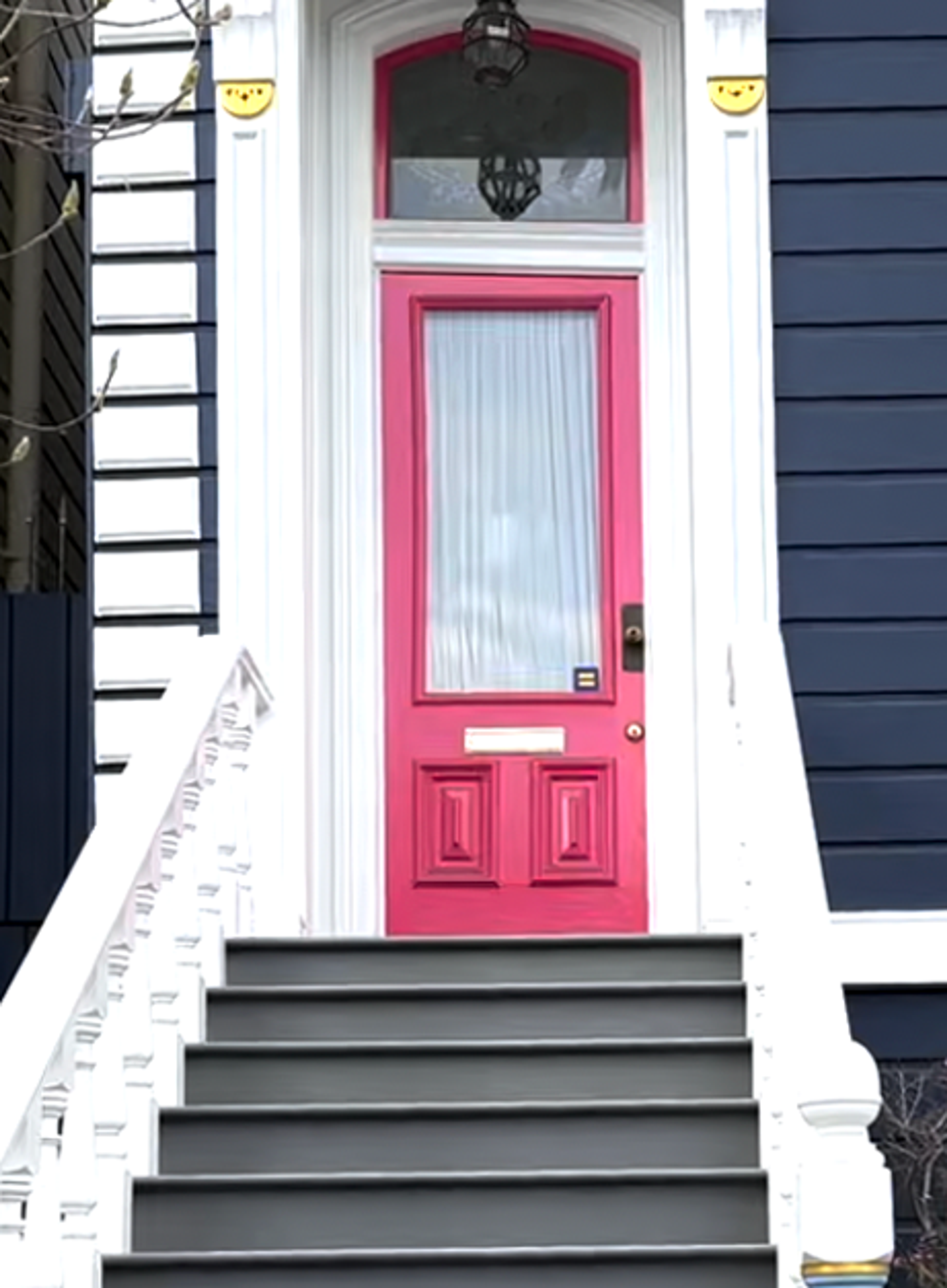 A medium close-up photo of a house entryway, the front door is painted pink.