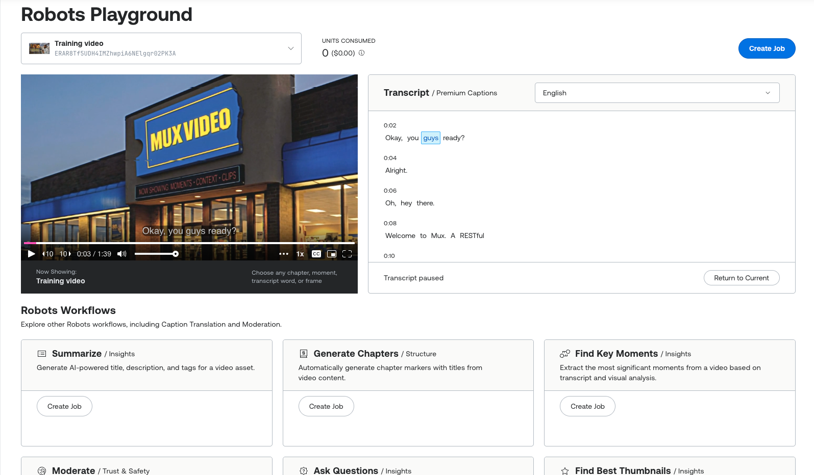 Mux Robots Playground dashboard with a "Training video" asset loaded and 0 units consumed ($0.00). The video player shows a retro video-rental storefront with a "MUX VIDEO" sign, next to a synced, time-stamped transcript panel. Below, under "Robots Workflows," are cards for Summarize, Generate Chapters, Find Key Moments, Moderate, Ask Questions, and Find Best Thumbnails, each with a Create Job button.