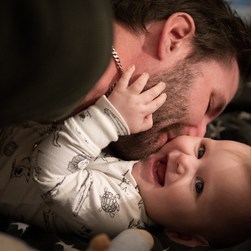 Dad kissing laughing baby