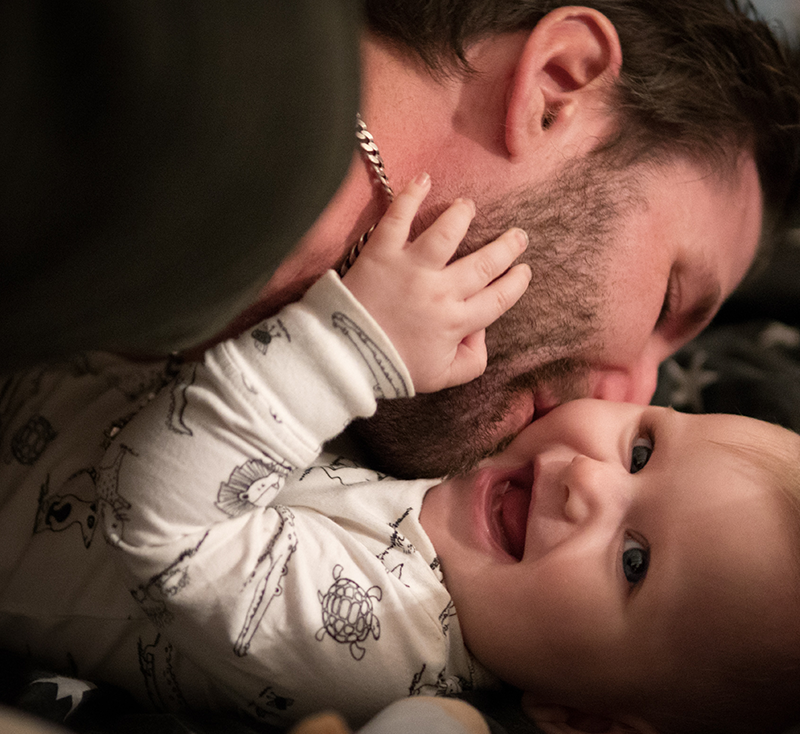Dad kissing laughing baby