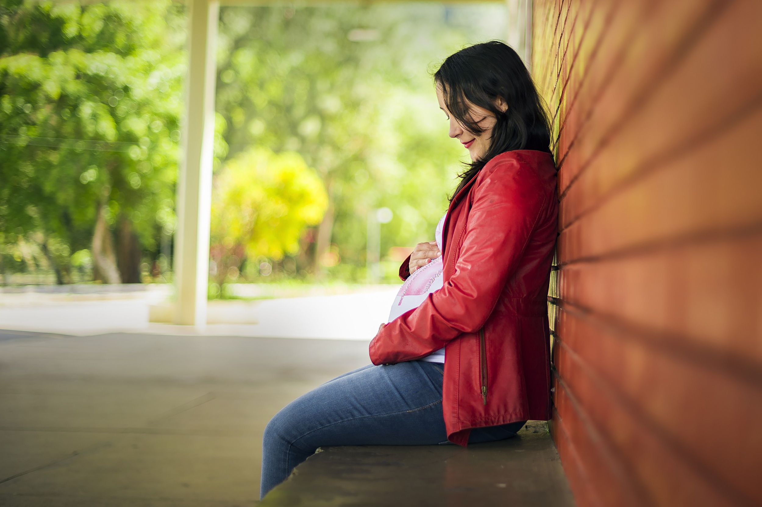 Pregnant mum sitting on outdoor bench holding her belly