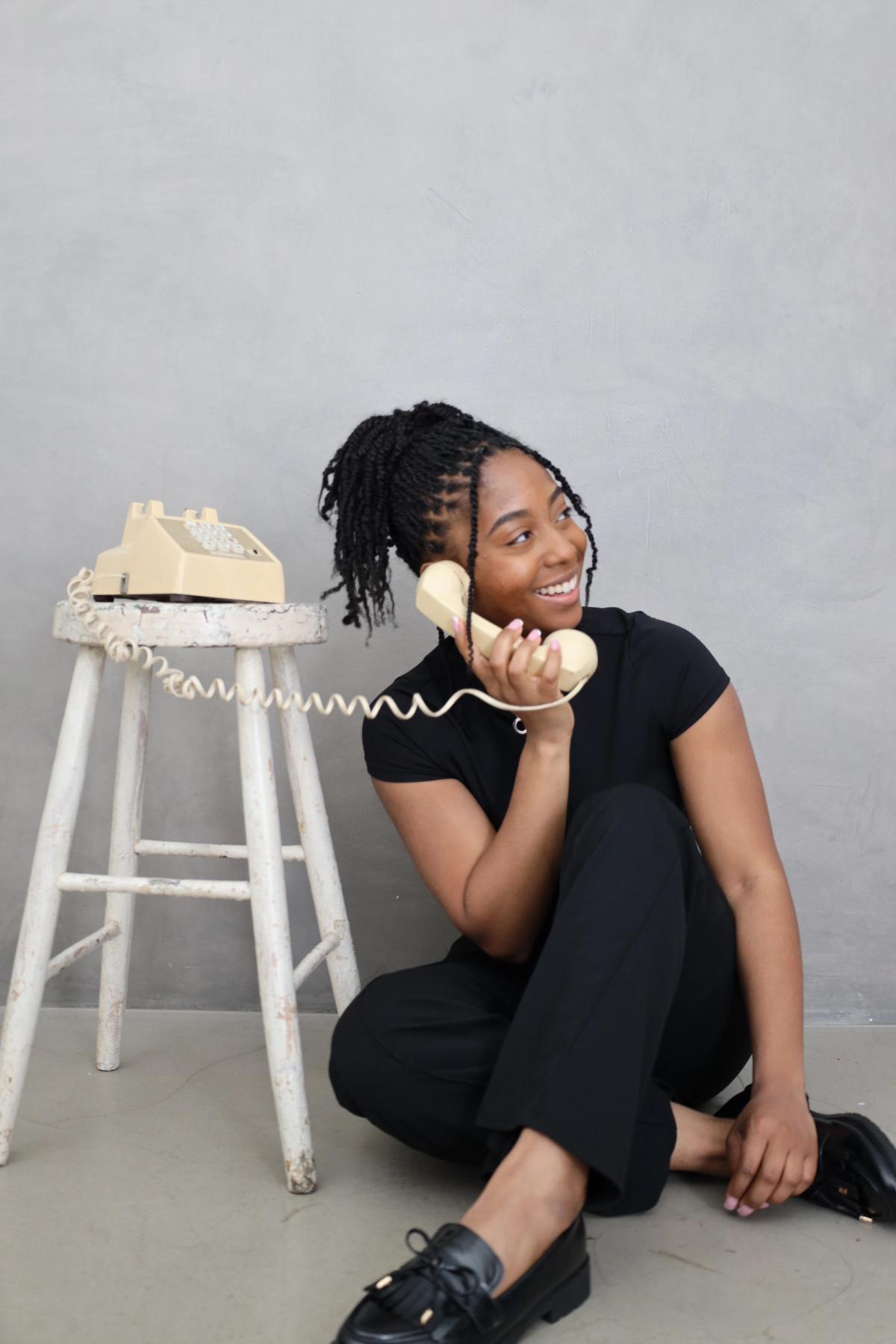 Smiling person laughing on a vintage cream telephone