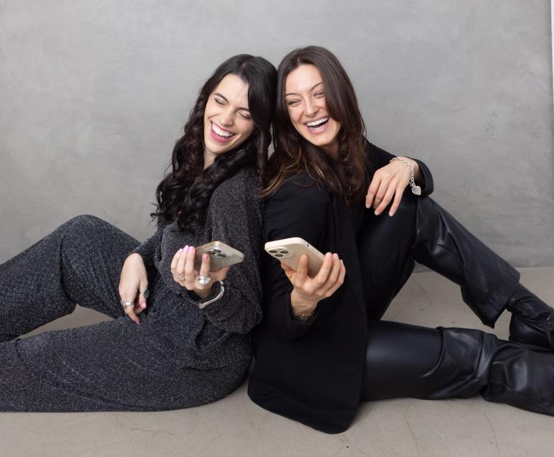 Two SociaLight Media team members laughing together while looking at their phones