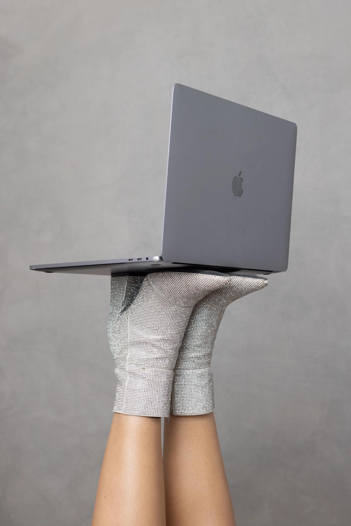 Laptop balanced on rhinestone boots — editorial website design shot