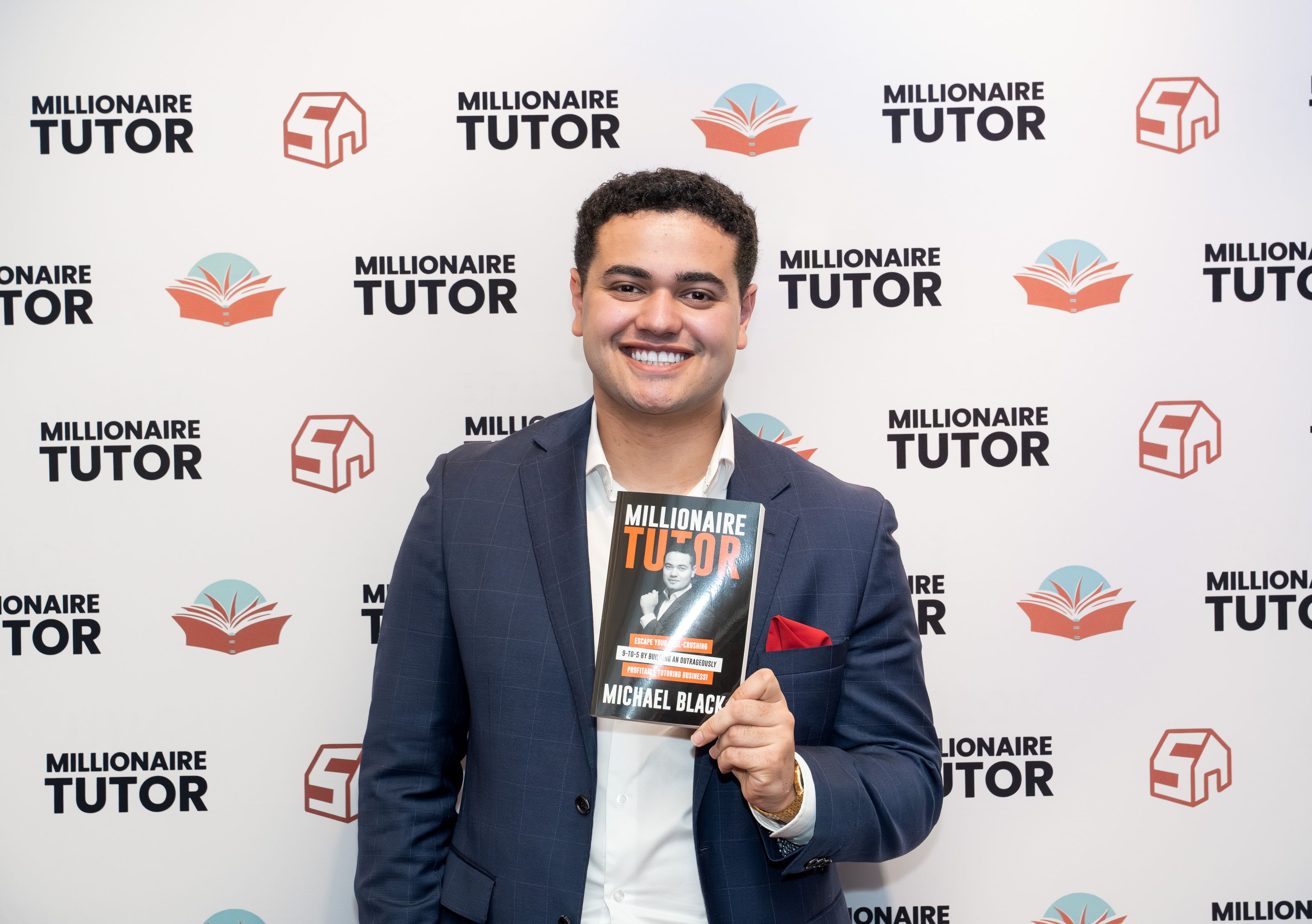 a man in a suit is holding a book in front of a wall .