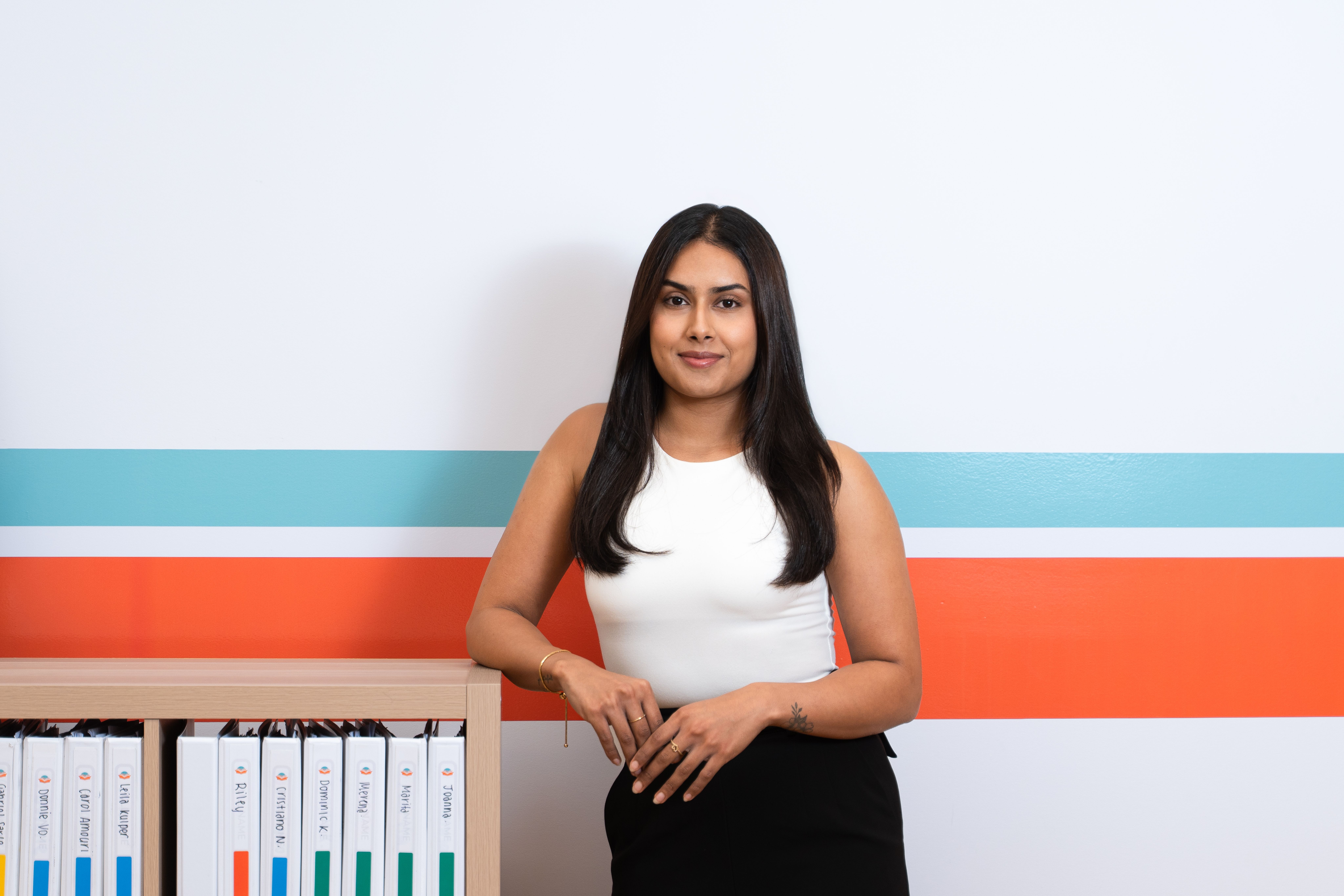 a woman is standing in front of a bookshelf with binders on it .