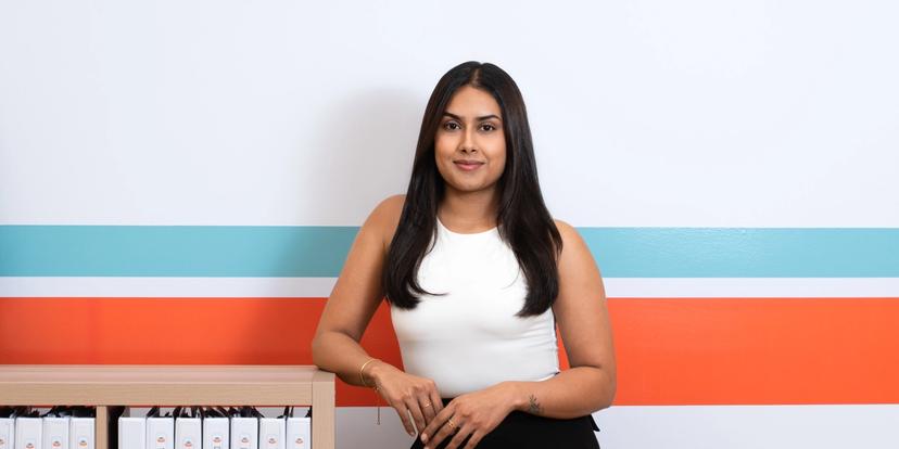 a woman is standing in front of a bookshelf with binders on it .