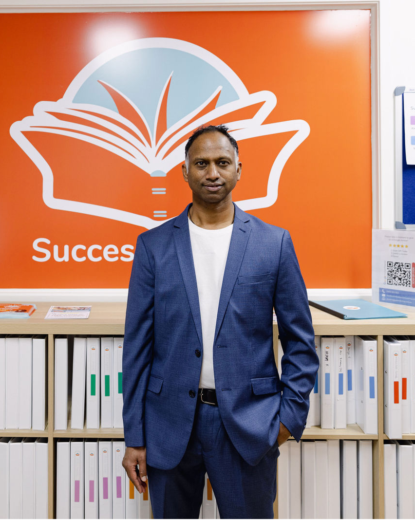 a man in a suit stands in front of a sign that says success