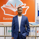 a man in a suit stands in front of a sign that says success