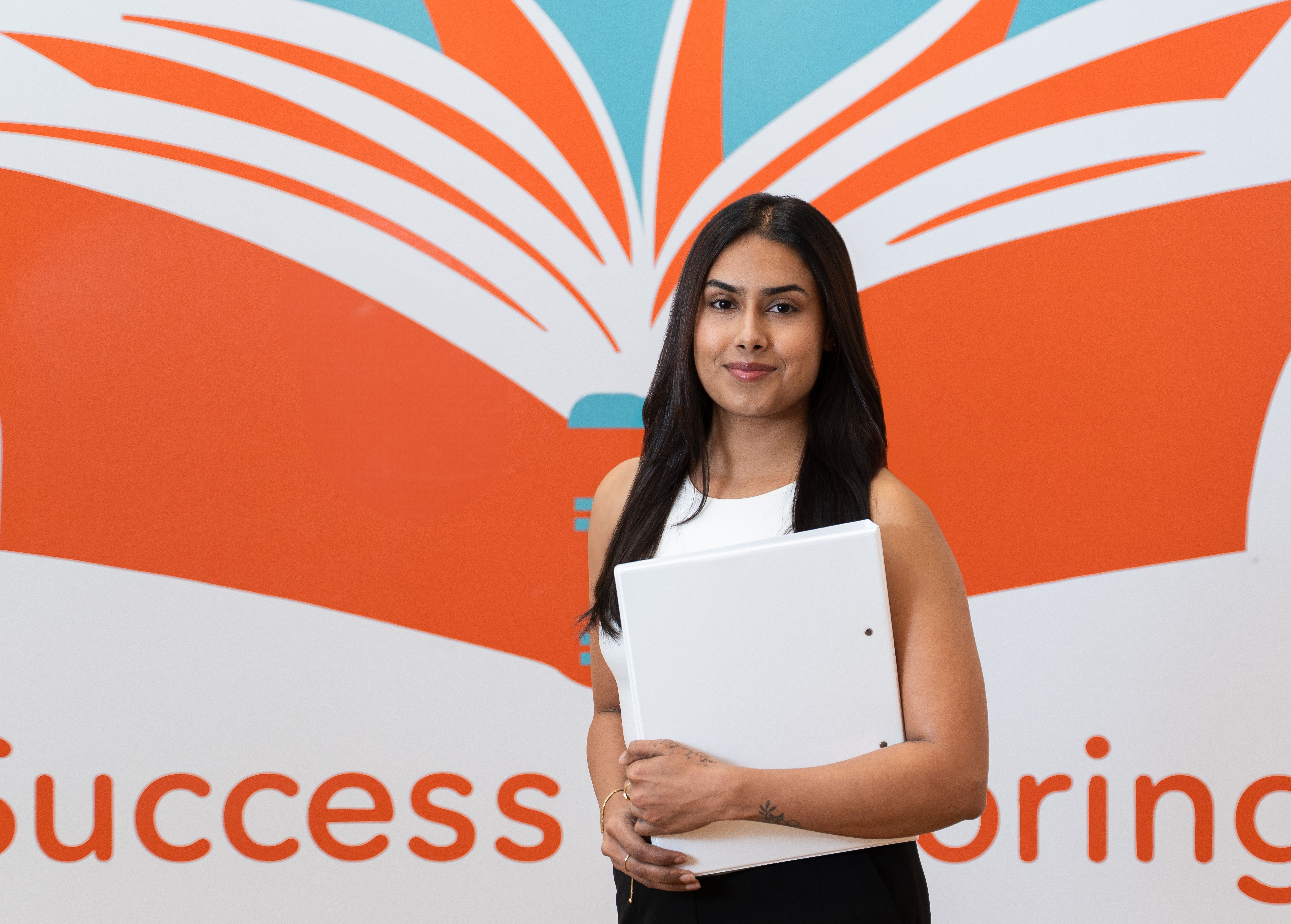 a woman is holding a white folder in front of a book .