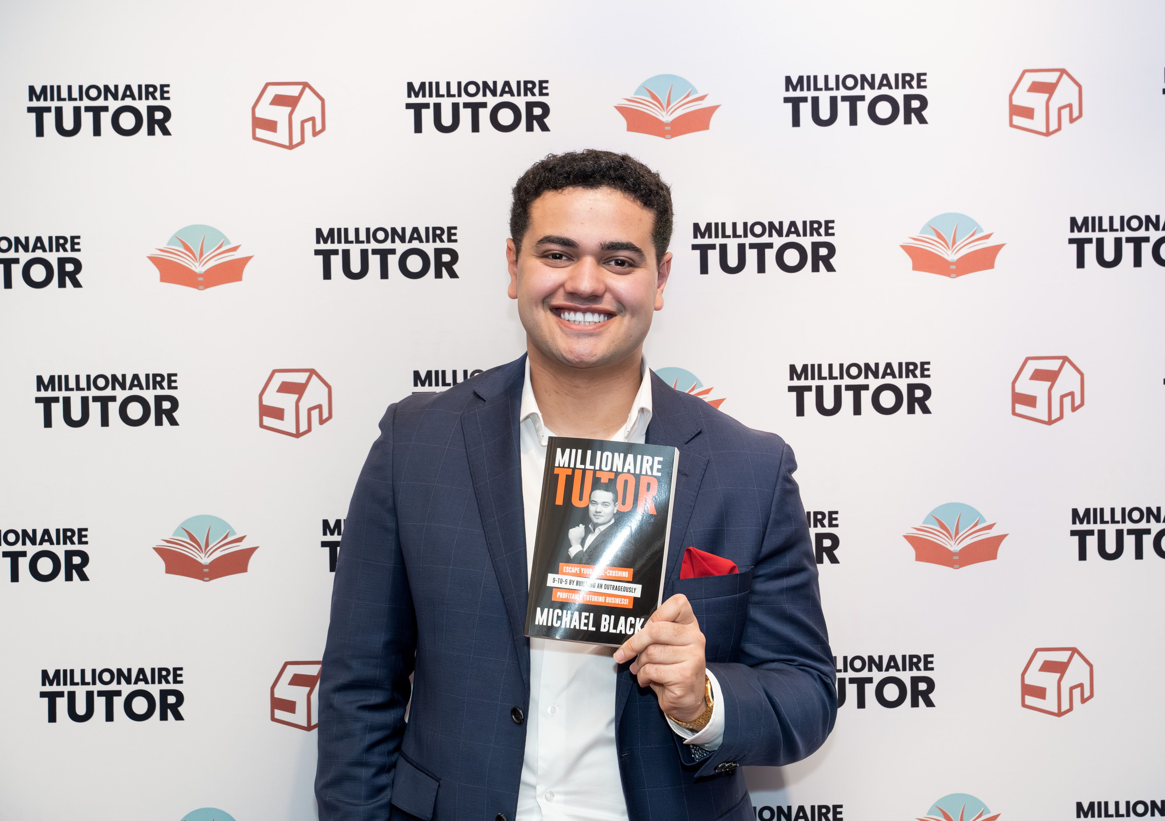 a man in a suit is holding a book in front of a wall .