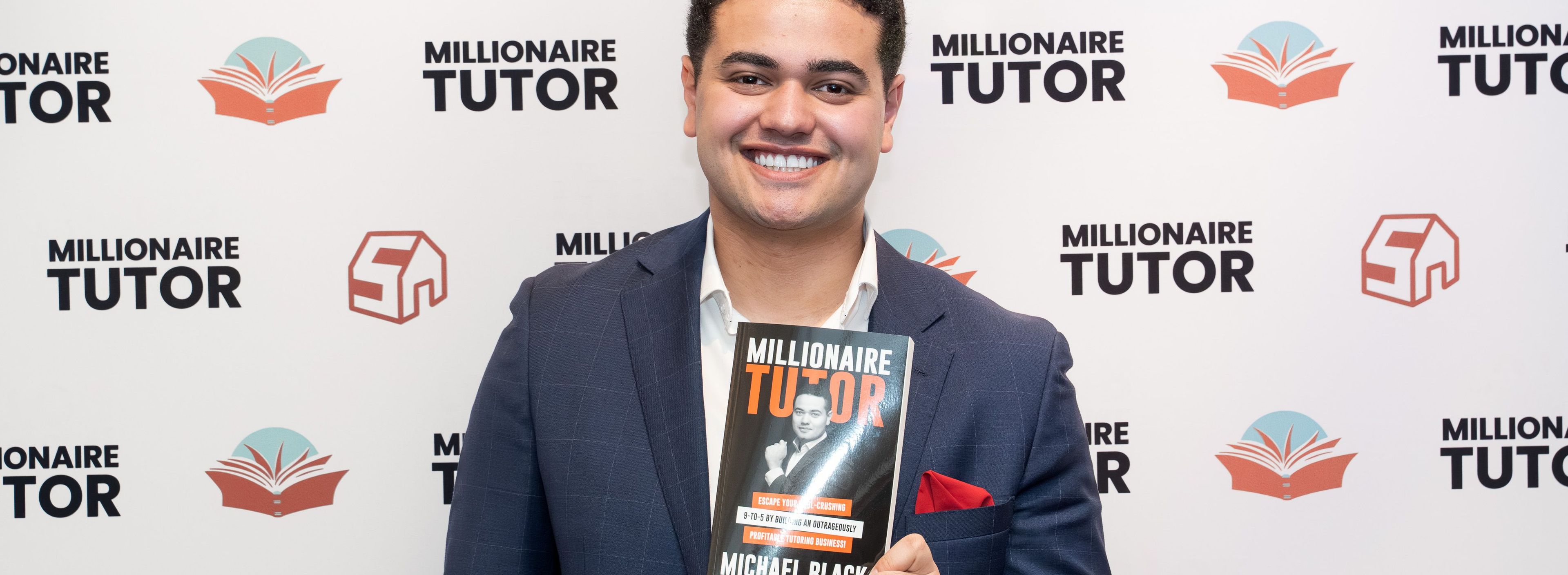 a man in a suit is holding a book in front of a wall .