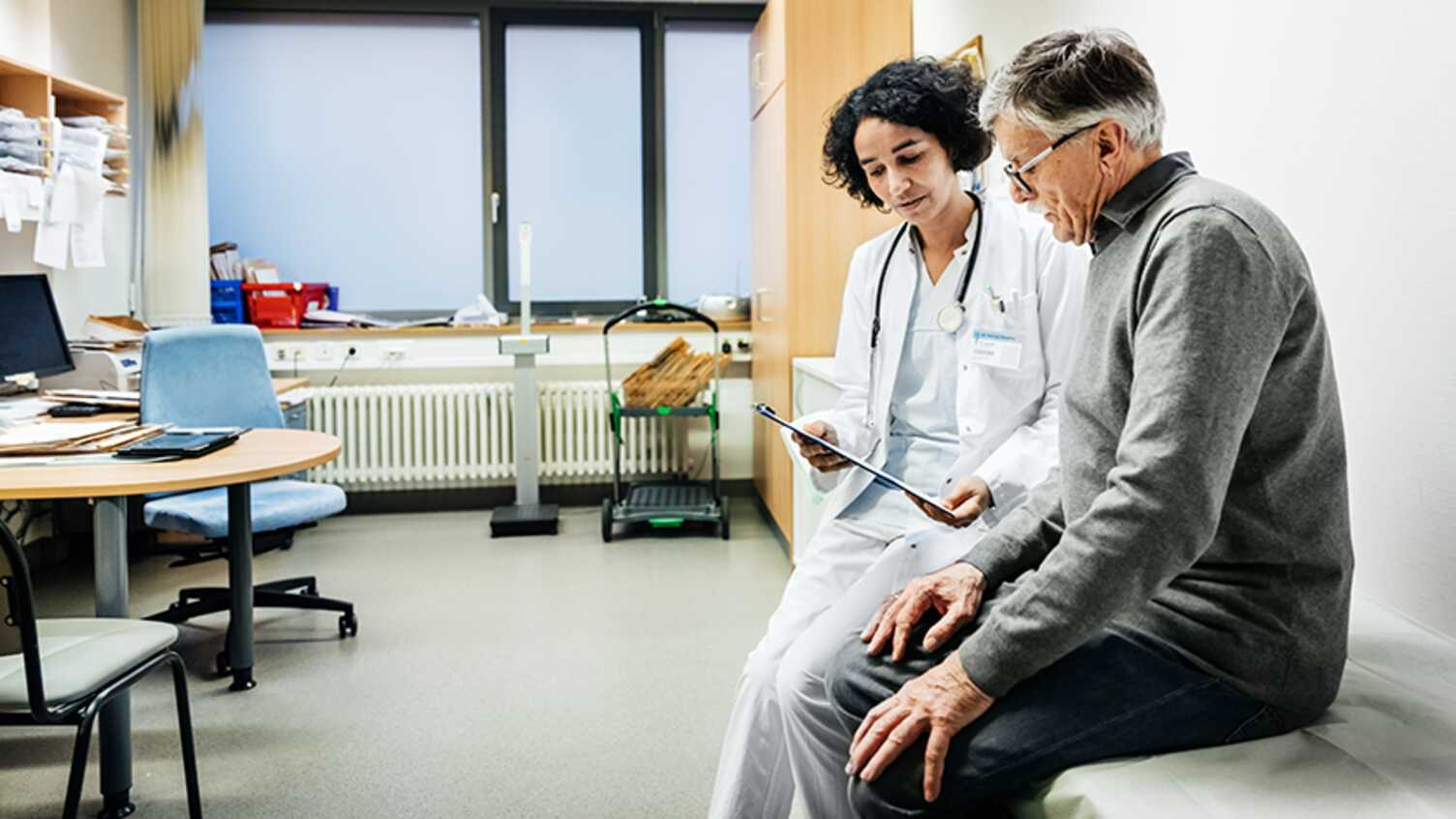 Doctor showing a tablet to an older patient during a clinic consultation