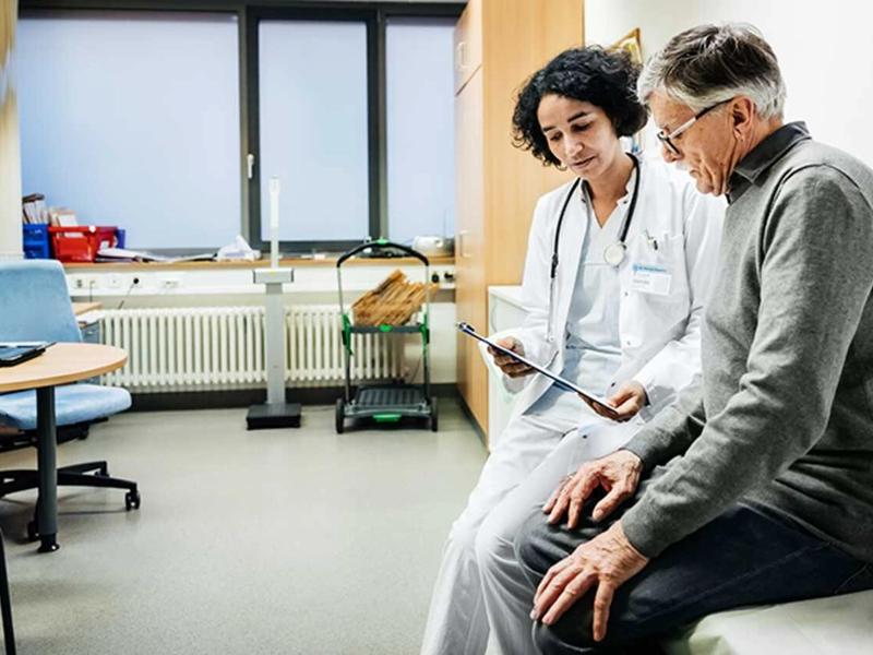 Doctor showing a tablet to an older patient during a clinic consultation