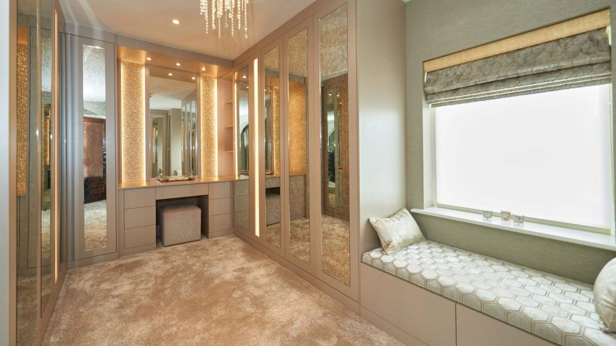 Fitted dressing room with mirrored wardrobes, illuminated dressing table and window seat