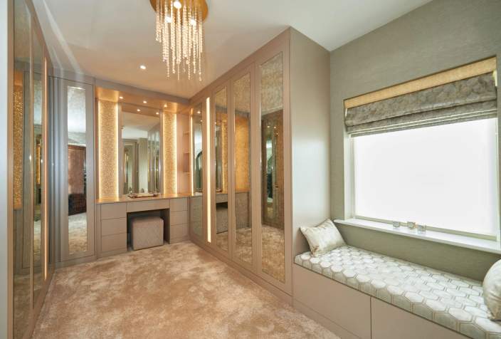 Fitted dressing room with mirrored wardrobes, illuminated dressing table and window seat