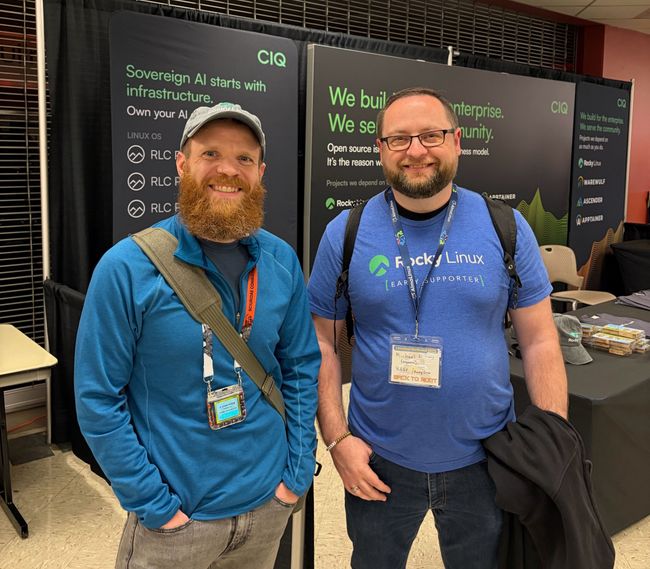 R. Leigh Hennig, CIQ's Open Source Fellow, and Michael Young, a contributing software engineer, at the Rocky Linux booth at LinuxFest Northwest 2026