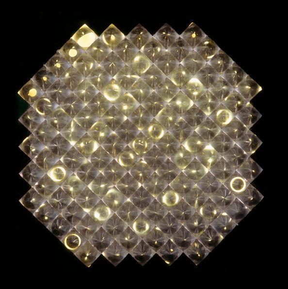 129 wabenförmig angeordnete, identische Plexiglaskegel befinden sich in einem schwarzen Kasten. Dieser ist nach vorne durch eine Glasscheibe verschlossen. Angetrieben von einem Motor bewegt sich im Objektkasten und unterhalb der Kegel verborgen eine Lochplatte über einer Lichtquelle. So entsteht ein Lichtspiel, bei dem in einem ungleichmäßigen Rhythmus Lichtkreise erscheinen, sich verzerren und wieder erlöschen. 