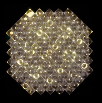 129 wabenförmig angeordnete, identische Plexiglaskegel befinden sich in einem schwarzen Kasten. Dieser ist nach vorne durch eine Glasscheibe verschlossen. Angetrieben von einem Motor bewegt sich im Objektkasten und unterhalb der Kegel verborgen eine Lochplatte über einer Lichtquelle. So entsteht ein Lichtspiel, bei dem in einem ungleichmäßigen Rhythmus Lichtkreise erscheinen, sich verzerren und wieder erlöschen.