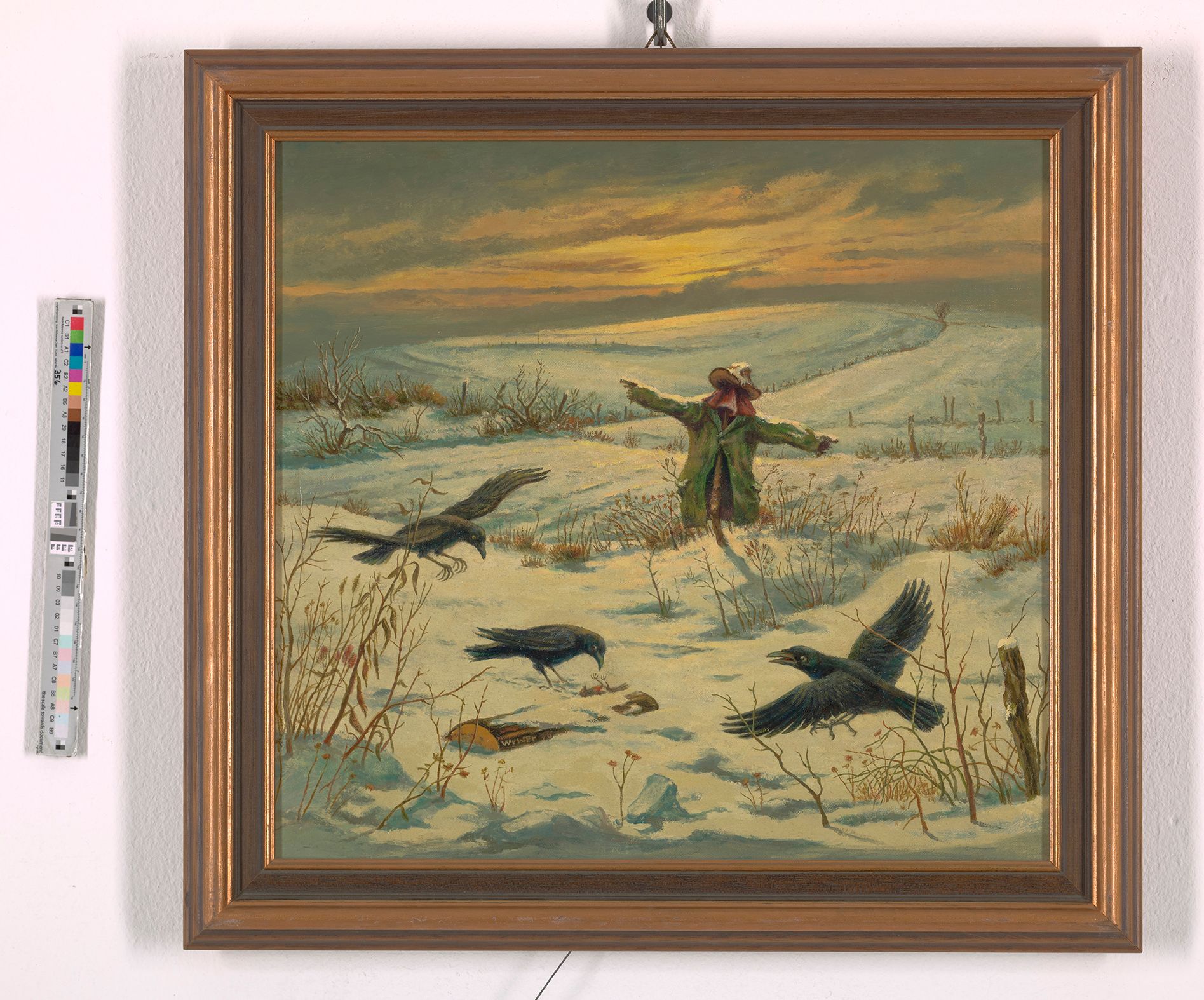 Gemälde. Verschneite Winterlandschaft bei Sonnenuntergang. Aus dem Schnee ragen mehrere Pflanzen und Zaunpfähle heraus. Außerdem steckt im Schnee eine Vogelscheuche. Vor dieser sind drei Raben. Zwei Raben sind noch im Anflug und einer pickt mit seinem Schnabel im Schnee herum.