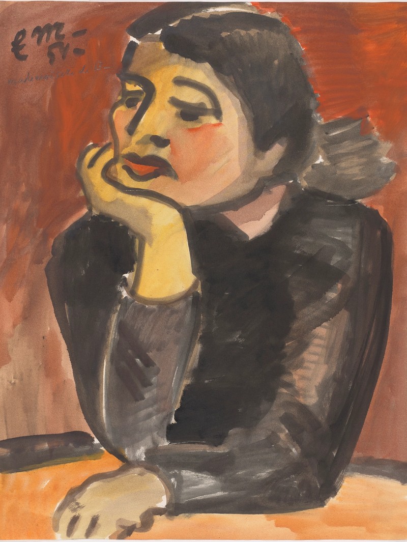 Eine Frau in einem schwarzen Kleid sitzt, die Hand gegen das Kinn gestützt, an einem Tisch vor einem roten Hintergrund.