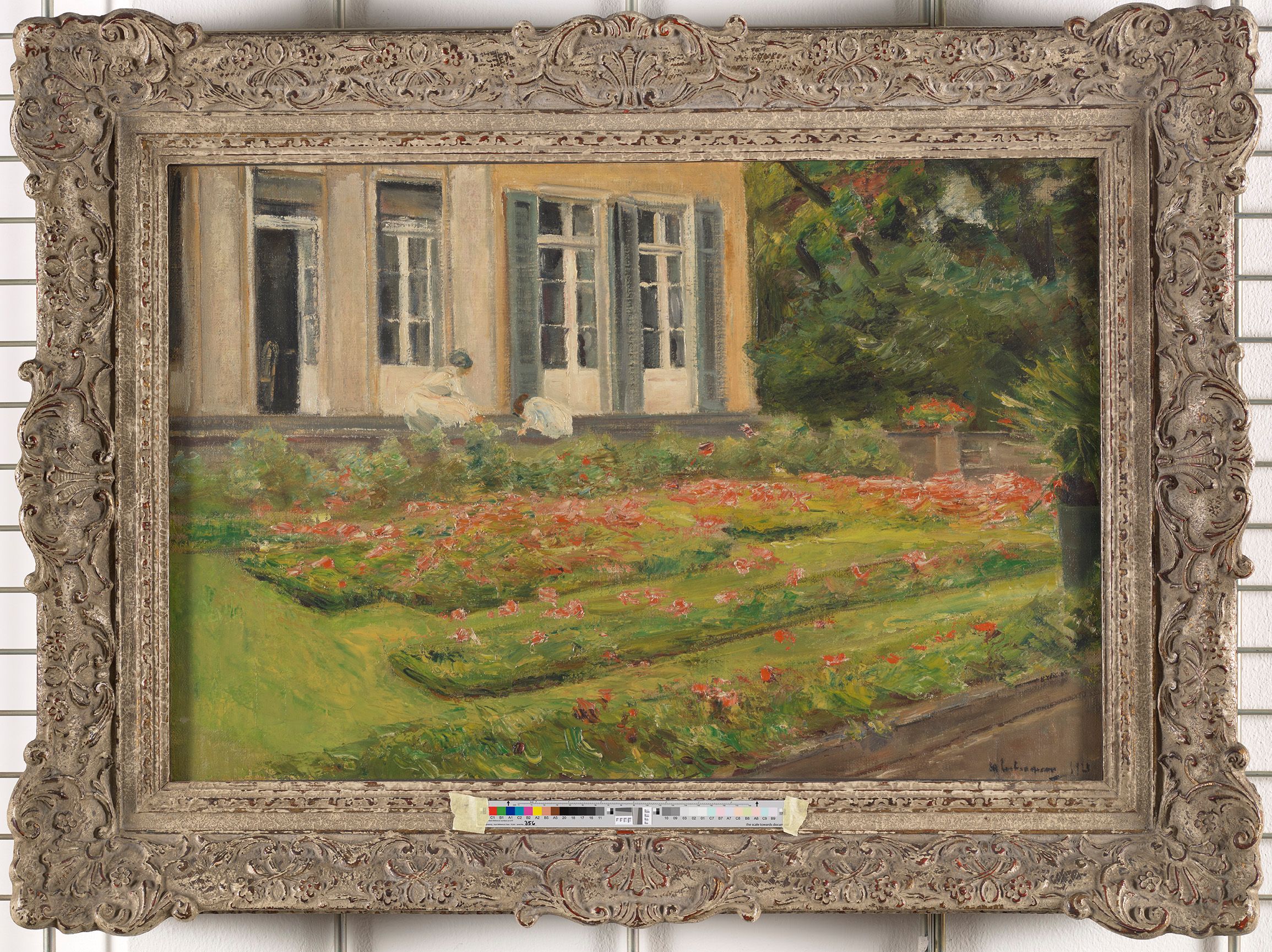 Gemälde. Außenfassade und Gartenstück. Das dargestellte Haus ist von außen weiß und hat große Fenster. Rechts neben dem Haus sind Bäume zu sehen. Vor dem Haus sind mehrere Blumenbeete mit roten Blumen. Zwei in weiß gekleidete Personen arbeiten an den Beeten.