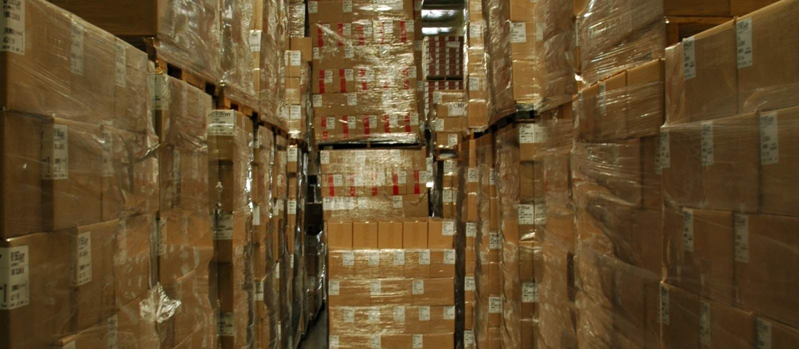 Depo koridorunda üst üste istiflenmiş kraft karton koliler