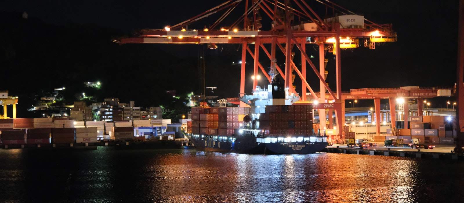 Gece vakti liman vinçleri ve yanaşmış bir konteyner gemisi